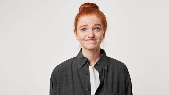 Frau mit roten Haaren schaut entschuldigend