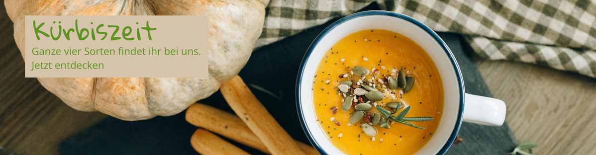 Ein Kürbis, Kürbissuppe und Brotstangen. Text: "Kürbiszeit. Ganze vier Sorten findet ihr bei uns. Jetzt entdecken."