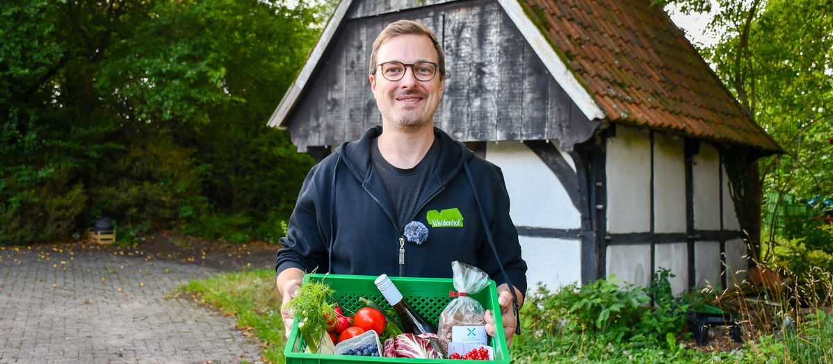 Mann hält eine Kiste mit Gemüse