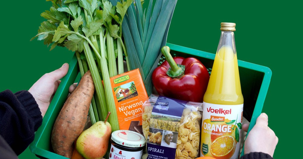 KI generiert: Eine grüne Kiste mit verschiedenen Lebensmitteln, darunter Gemüse, Saft und Nudeln.