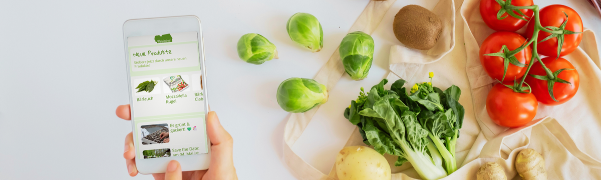 KI generiert: Ein Smartphone zeigt eine Gemüse-App; daneben liegen verschiedene Gemüsearten wie Tomaten und Rosenkohl.