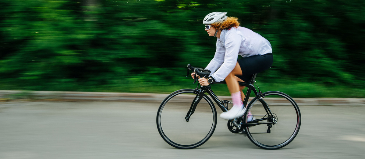 Eine Person fährt schnell auf einem Rennrad auf einer Straße entlang.