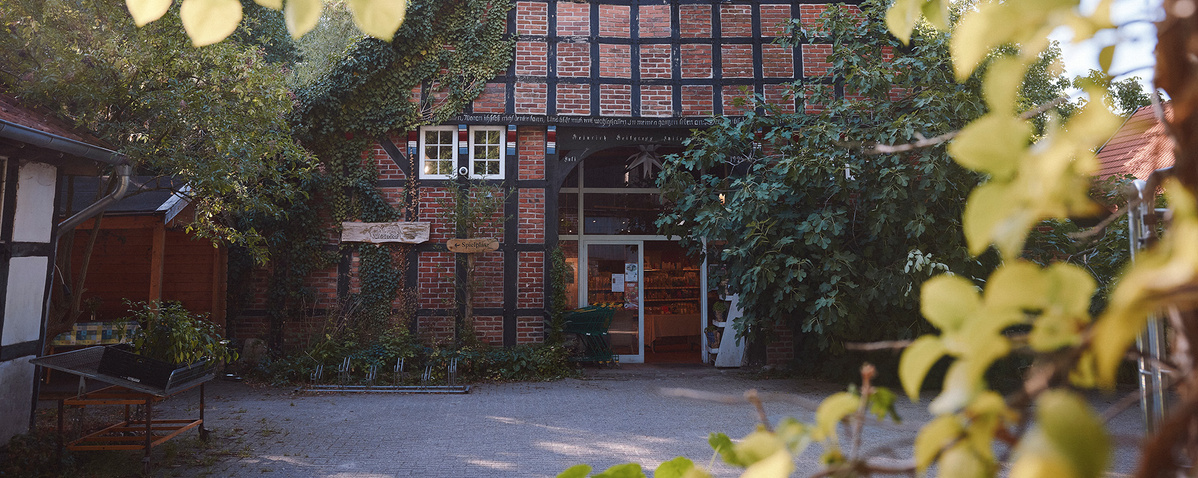 Fachwerkhaus mit Eingangsbereich, umgeben von Bäumen und Pflanzen.