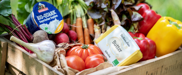 KI generiert: Eine Holzkiste voller frischer Gemüse, Bio-Quark und Butter.