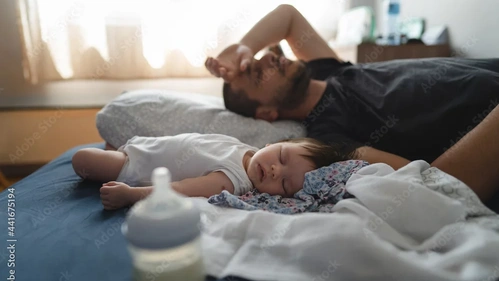 Vater schläft mit Baby im Bett