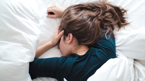 Eine Frau schläft in einem Bett mit weißer Bettwäsche