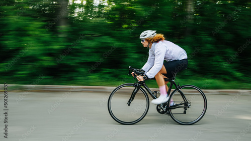 KI generiert: Eine Person fährt schnell mit einem Rennrad auf einer Straße, hinter grüner, unscharfer Landschaft.
