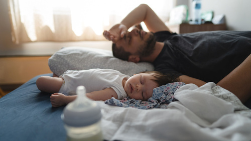 Vater schläft mit Baby im Bett