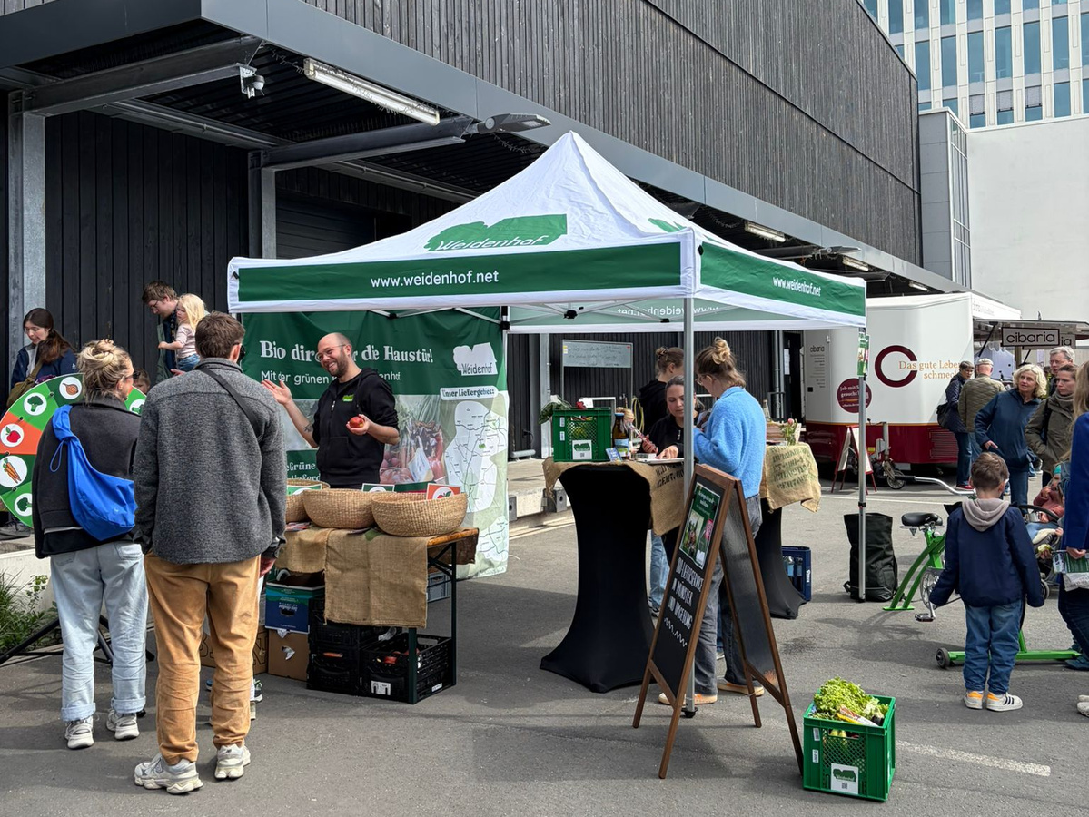 KI generiert: Ein Marktstand mit einem weißen Pavillon; Aufschrift: "www.weidenhof.net".