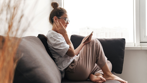 Frau mit Handy auf dem Sofa