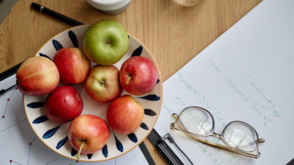Frisches Obst und ein Notizbuch auf einem Holztisch.