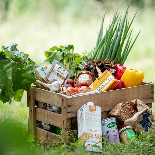 KI generiert: Eine Holzkiste gefüllt mit frischem Gemüse und Bio-Produkten. Enthält: Hafer Drink, Tofu, Gemüse, Uisan's Bio.